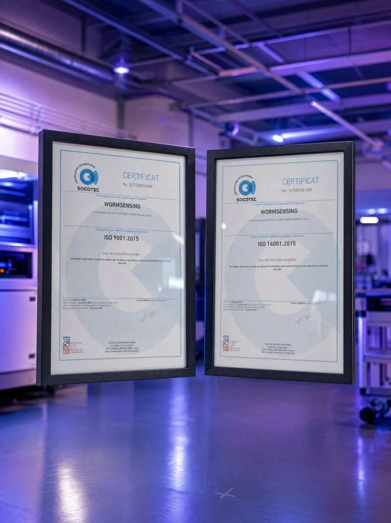 Wormsensing's ISO 9001:2015 and ISO 14001:2015 certificates, framed in the lab